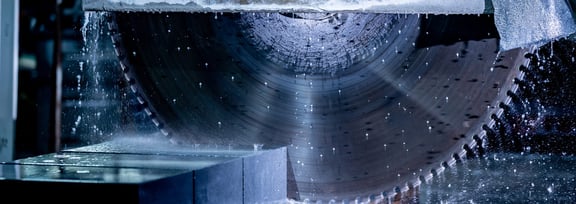 Große rotierende Schleifscheibe schleift nassen Granitblock