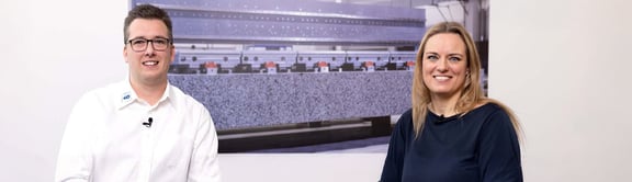 Christopher Reitz von REITZ Natursteintechnik und Moderatorin im Podcast-Studio vor dem Bild eines Granitbauteils; Diskussion über Maschinenbau, Naturstein und hochpräzise Fertigung.